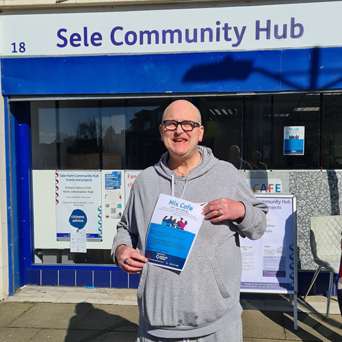 Michael outside Sele Community Hub with Mix Cafe posters